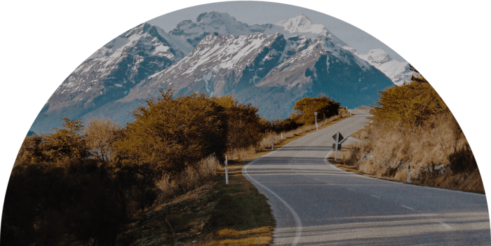 A scenic image of a mountain road in new zealand with some mountains in the background